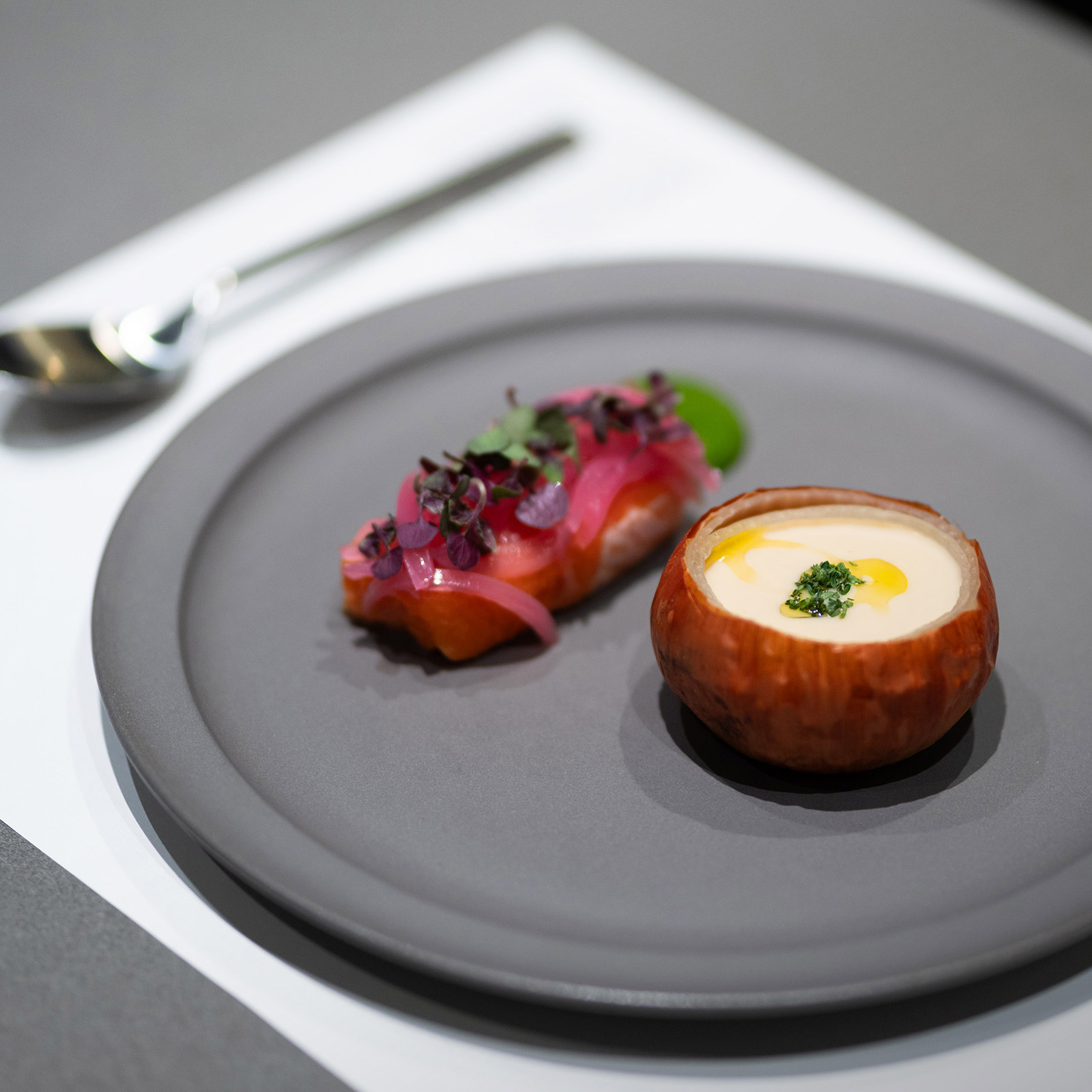 A plate with onion potage and marinated salmon.