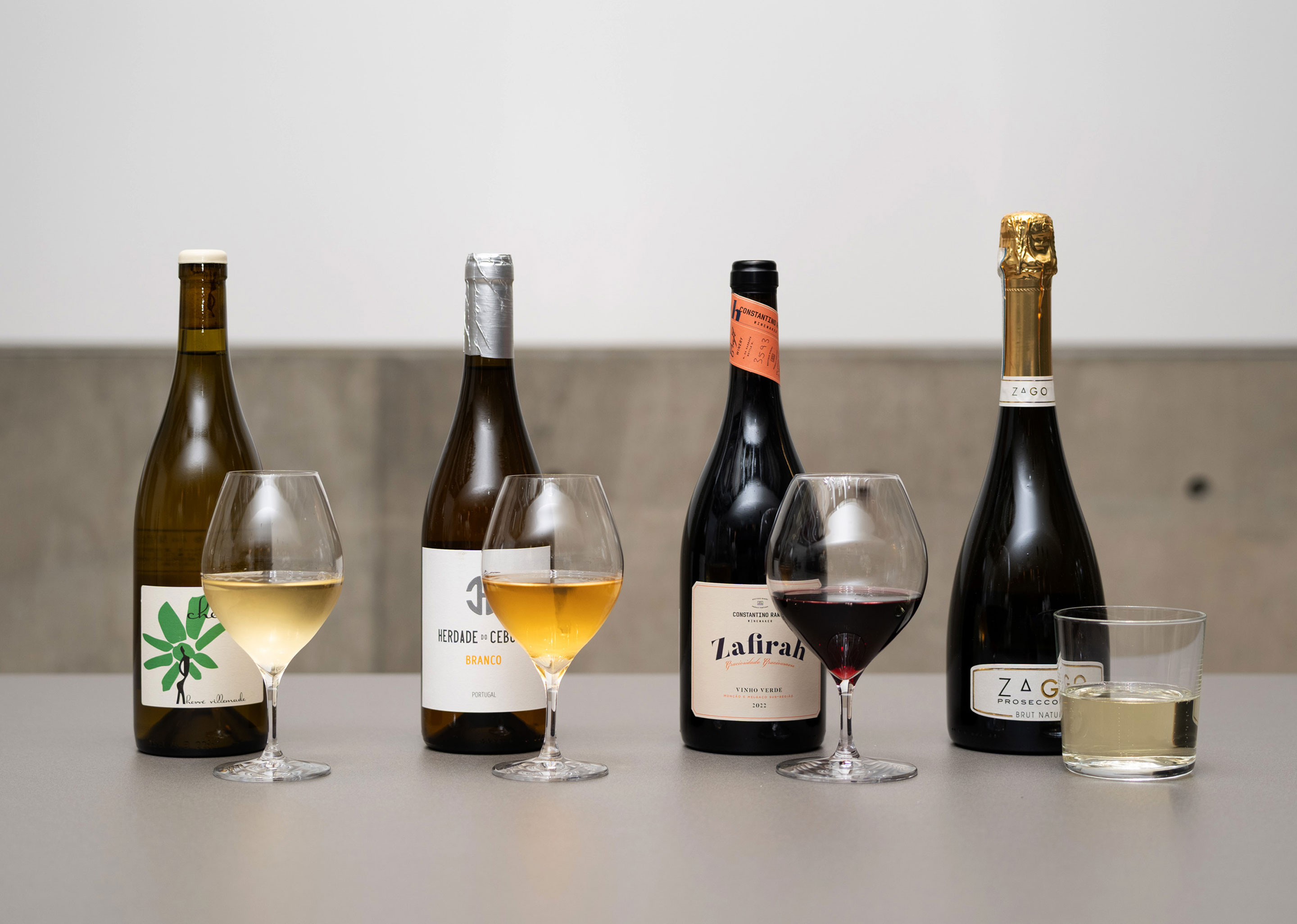 A photo of four types of wine poured into glasses and their bottles.