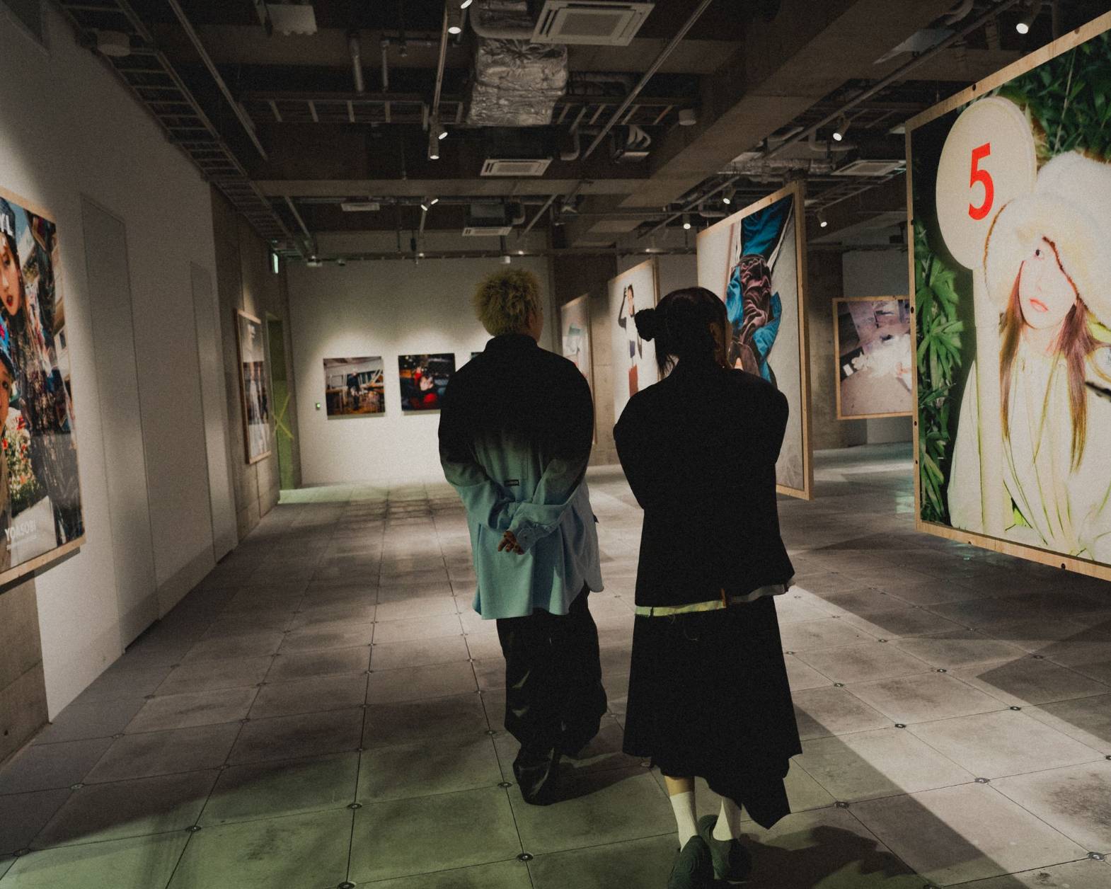 A hands-on experience. The two members of YOASOBI viewing the exhibit space with recently shot photos scattered about.