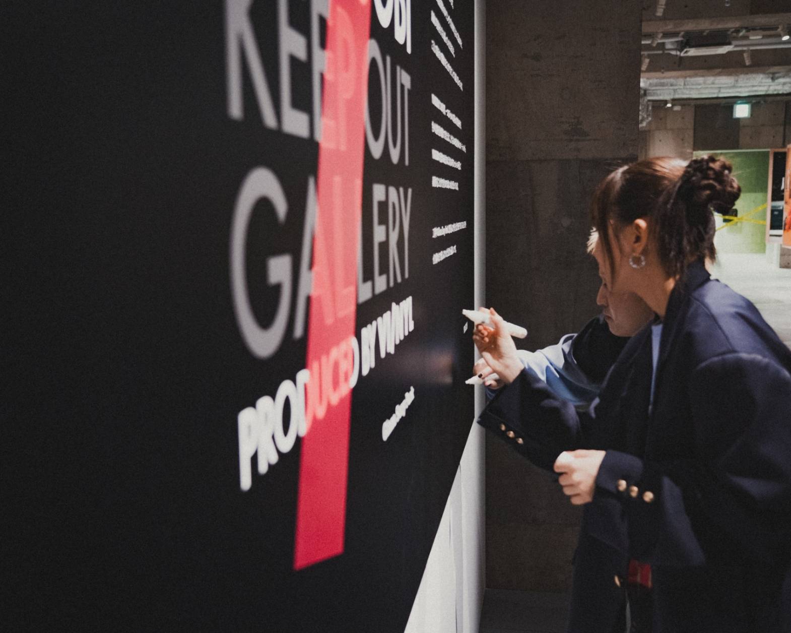 A hands-on experience. The two members of YOASOBI signing their autographs on the display board in the exhibit space.