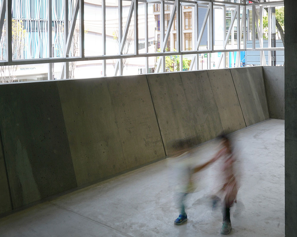 Two children are running down a concrete corridor.
