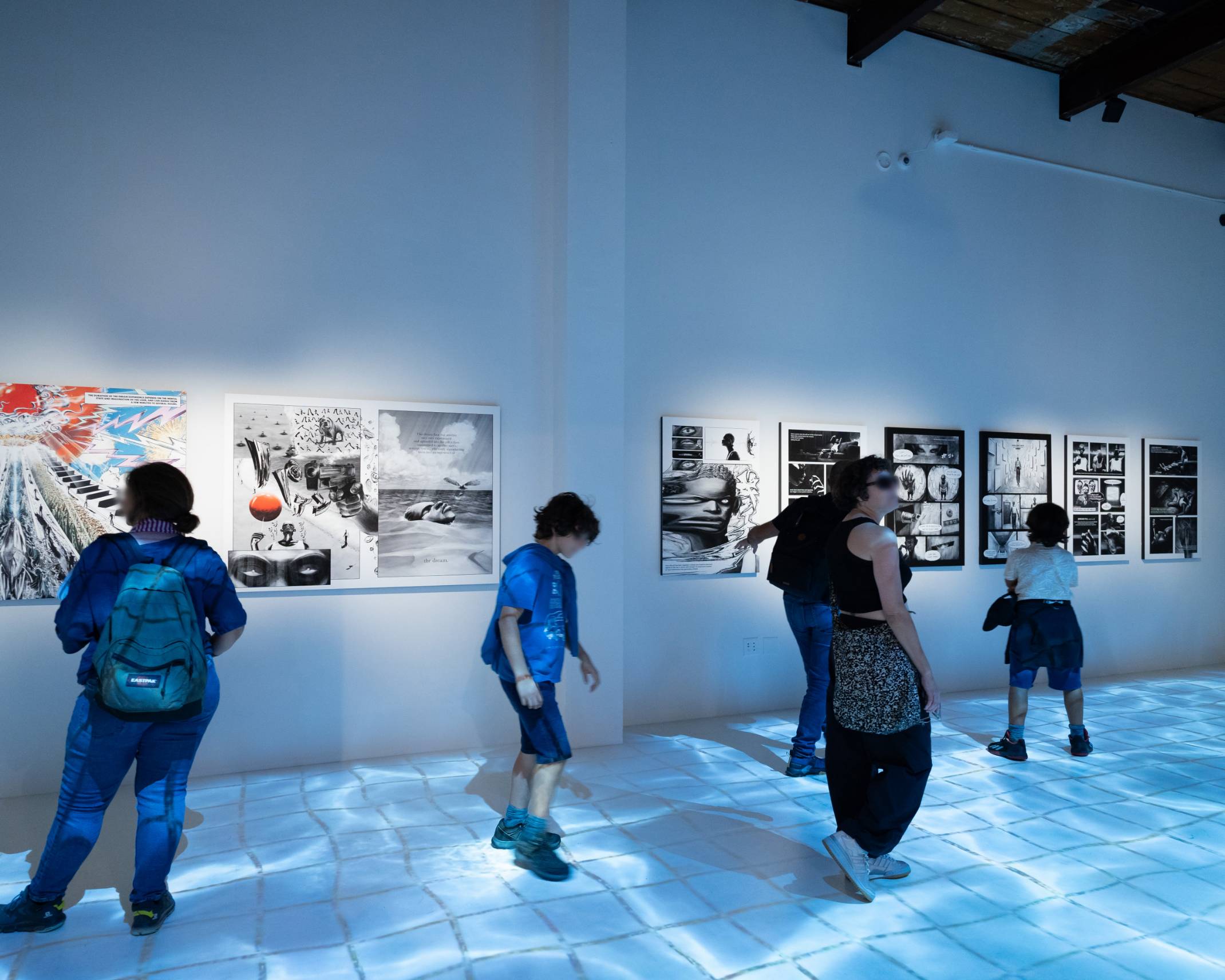 A hands-on experience. Visitors look at the manga exhibited on the walls and enjoy the interaction of walking on the puddles projected onto the floor.