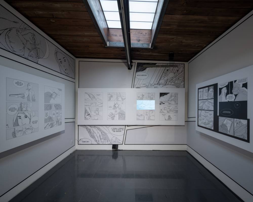 Exhibit. Light shines gently in through the skylight on the second floor of the venue, where there are manga exhibited on the walls.